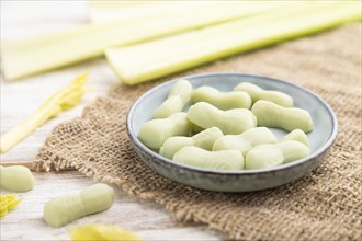 Jelly celery candies on white wooden background and linen textile. close up, side view, selective