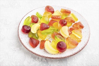 Various fruit jelly candies on plate on gray concrete background. close up, copy space