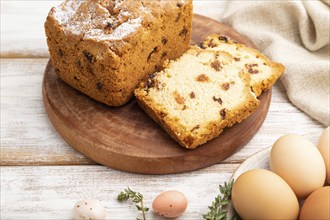 Homemade easter pie with raisins and eggs on plate on a white wooden background and linen textile.