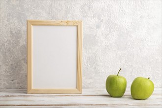 White wooden frame mockup with green apple on gray concrete background. Blank, vertical