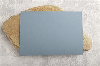 Blue paper business card, mockup with natural stone on gray concrete background. Blank, flat lay,