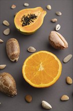 Ripe cut papaya, orange, seashells on gray pastel background. Side view, copy space. Tropical,