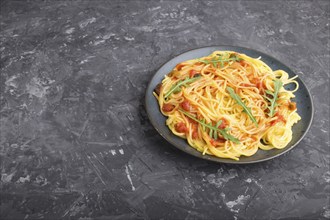 Corn noodles with tomato sauce and arugula on a black concrete background. Side view, close up,