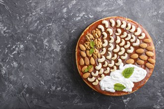 Homemade cake with caramel cream and nuts on a black concrete background. top view. flat lay, copy