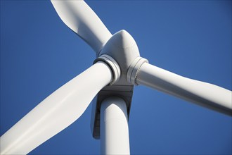 Close up of center of white wind mill turbine in front of blue sky. Generative Ai, AI generated