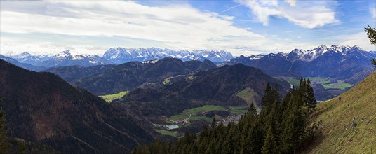 Panoramic view of the snow-covered Chiemgau mountains and green hills above the village of