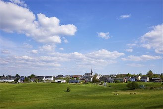 Landscape with meadows and shadows of clouds under a blue sky with cumulus clouds and a long shot