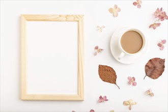 Composition with wooden frame, brown beech autumn leaves, hydrangea flowers and cup of coffee.