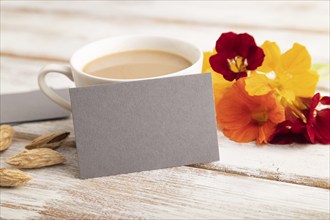 Gray paper business card mockup with orange nasturtium flower and cup of coffee on white wooden