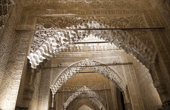 Illuminated view at night of richly decorated Islamic stonework arch Alhmabra palaces, Granada,