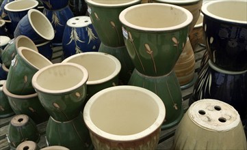 Colourful ceramic pots piled up on display in a garden centre, UK