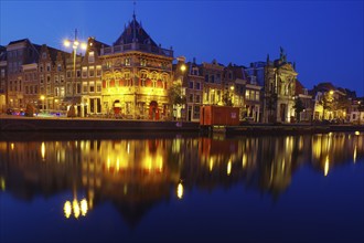 Evening atmosphere in a city with illuminated buildings reflected in the calm waters of a canal,