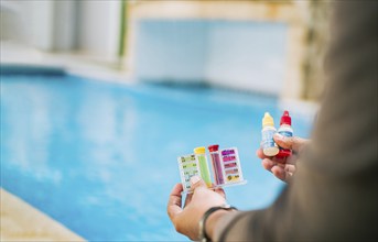 Hand holding tester kit to measure chlorine and ph in swimming pools. Person testing the PH of the