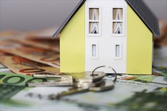 Concept photo with model house, euro notes and coins