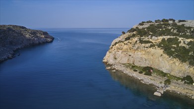 Drone shot, Rocky coast with a calm bay and blue water surrounded by natural beauty and sky,