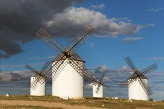 Windmills in a vast landscape under a sky with dramatic clouds and sunlight, Windmills, Campo de