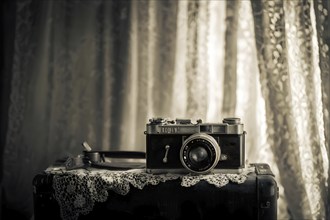 Vintage film camera surrounded by black and white photos in soft sunlight, AI generated