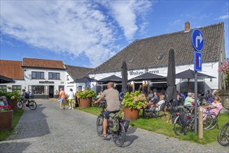 Tourists at sidewalk café of pub Den Ouden Toren on market square in the village Lissewege near