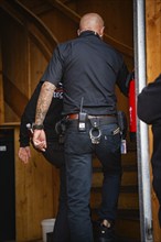 Security guard in black uniform walks up a wooden staircase, Canstatter Wasen, Stuttgart, Germany,