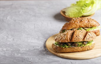 Sprats sandwiches with lettuce and cream cheese on wooden board on a gray concrete background. side