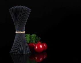 Bouquet, black spaghetti Nori, with ingredients, tomatoes and basil, on a black background,