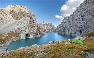 Green tent at the turquoise mountain lake Kol Suu with rocky steep mountains, Kol Suu Lake, Sary