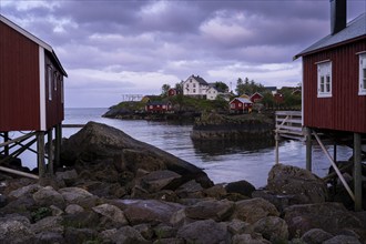 Typical red wooden houses on wooden stilts (rorbuer) in Nusfjord, white houses in the background.