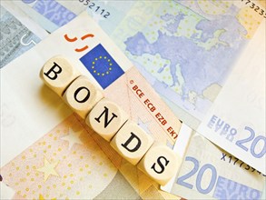 Wooden cube with the inscription 'BONDS' on a background of euro banknotes, outline of the European