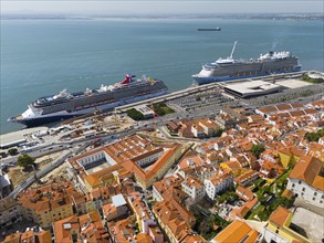 Harbour with cruise ships next to a city with red roofs on the coast of the sea, aerial view,