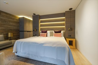 Modern bedroom with large bed, backlit wall and wood panelling, Mayrhofen, Zillertal, Austria,