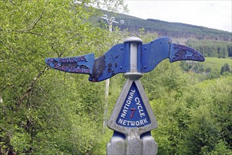 National Cycle Network signpost amidst green trees beside a path, Callander, Highlands, Scotland,