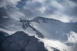 Dramatic mountain landscape, mountain valley, behind glaciated and snow-covered mountain peak Pik