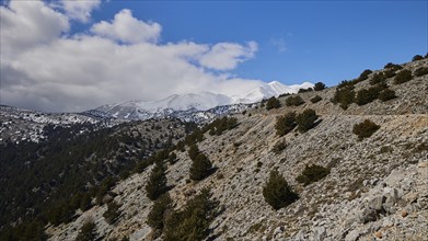 Unpaved road to the Niatos Plateau, mountain landscape with some snow remains and cloudy sky, near