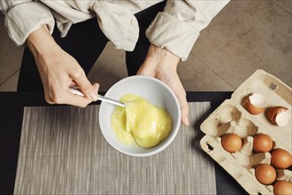 Top view of hands of woman whipping eggs in an omelette bowl