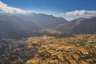 Aerial view of a valley with fields, crossed by sunbeams and surrounded by mountains, Askifou