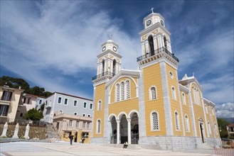 A yellow church with two clock towers under a blue sky, in front of a paved square, Cathedral,