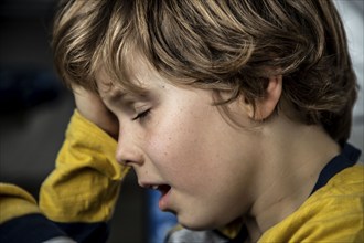 Kind mit Kopfschmerzen, Junge 9 Jahre alt, mit schmerzverzerrtem Gesicht, symbolisches Bild