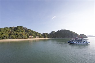 Excursion boat anchored on the beach of Monkey Island, behind the karst rocks in Lan Ha Bay, Halong