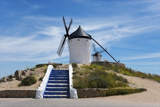 White windmill on a hill with blue steps and a clear blue sky in the background, Consuegra, Toledo,