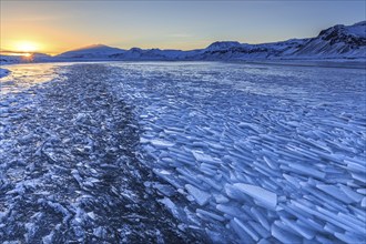 Ice floes on a lake in front of snowy mountains, sunset, evening light, snow, winter, Snaefellsnes,