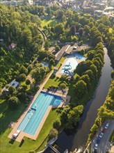 Aerial view of an extensive swimming pool complex with several pools, surrounded by trees and