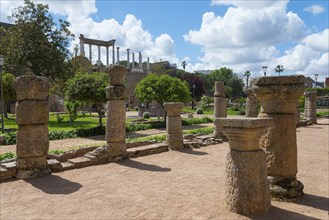 Ancient stone columns and ruins in a green garden under a sunny sky, a remnant of Roman