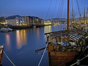 Harbour at night with illuminated boats and modern buildings in the background, Nidarelva,