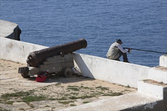 Cliff fishermen and historic cannon in the Fortaleza de Sagres, Vila do Infante, Sagres, Algarve,