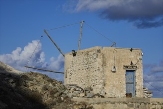 Old stone mill under clear blue sky, surrounded by clouds, Colourful mountain village, Morning