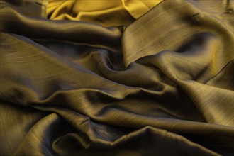 Fragment of yellow and green tissue. Side view, synthetic textile background and texture. wave