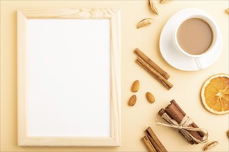 Composition with wooden frame, almonds, cinnamon and cup of coffee. mockup on orange background.