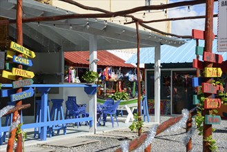 A Caribbean market with colourful signs and souvenirs under an outdoor wooden structure, Bayahibe,