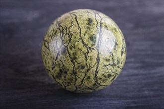 Green serpentine sphere on a black background, close up