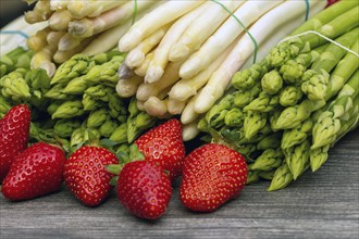 Green asparagus, white asparagus and fresh strawberries decorated on a rustic wooden table